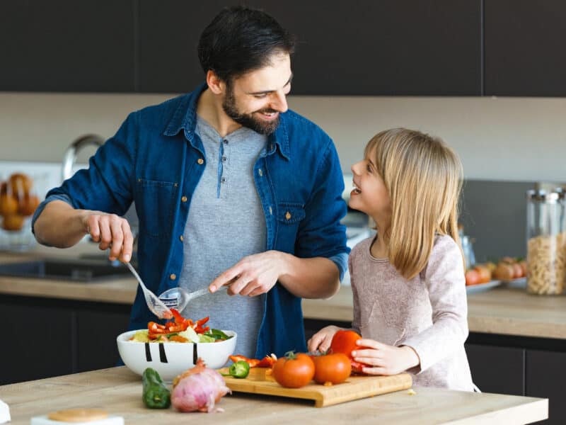 Shot of attractive young man with her little cute daughter making salad together on kitchen at home